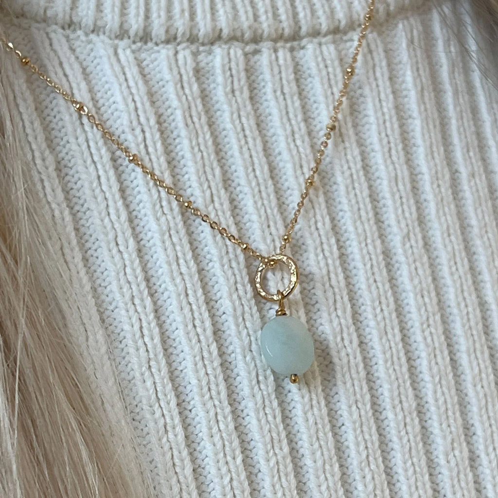 The necklace is being worn. The gold chain holds a gold hoop from which the amazonite hangs