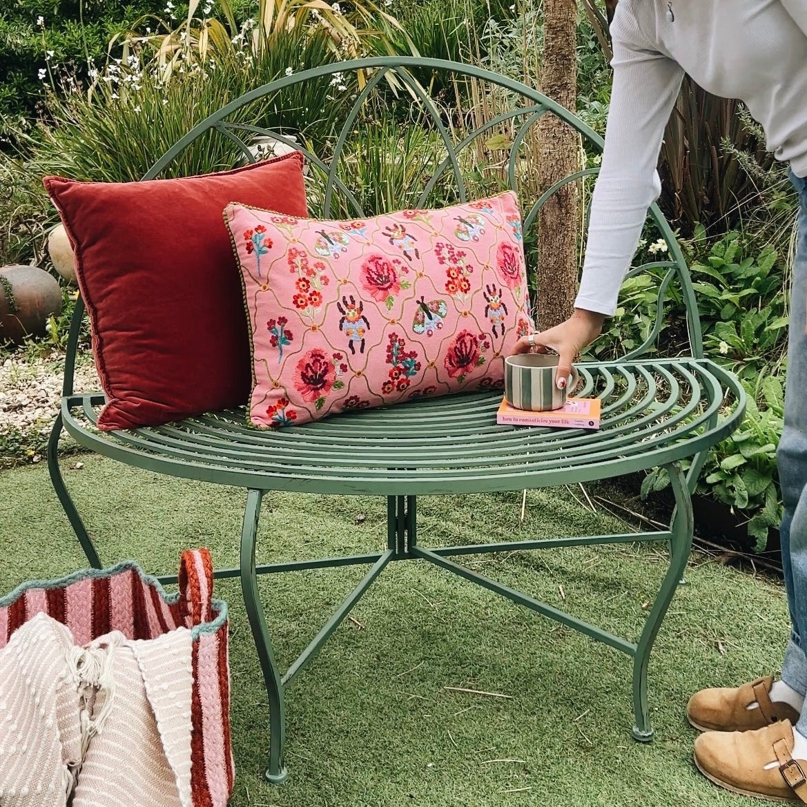 Person arranging cushions on a garden chair with a floral pattern - Light Green Semi-Circle Petal Outdoor Bench - Uneeka Home Lifestyle