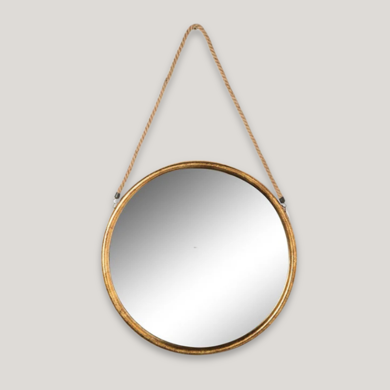 A round gold framed mirror with a rope at the top for hanging