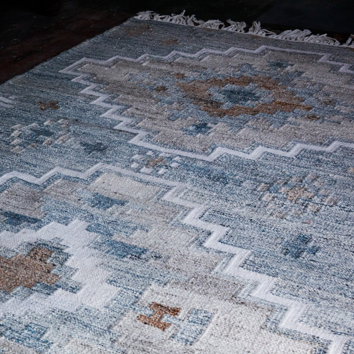 Close-up of a patterned rug with blue, grey, and white colours. Uneeka Large Blue & Cream Geometric Recycled Plastic Rug.
