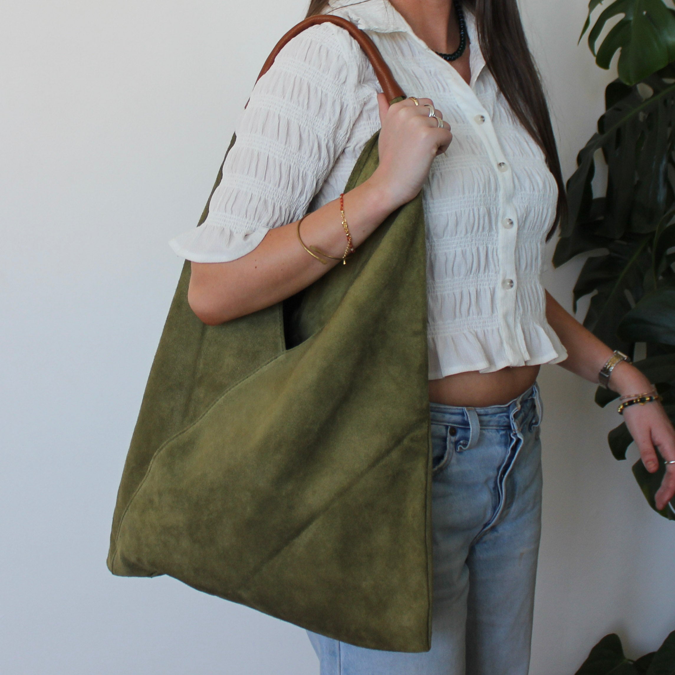 Person holding a green suede handbag with a white background