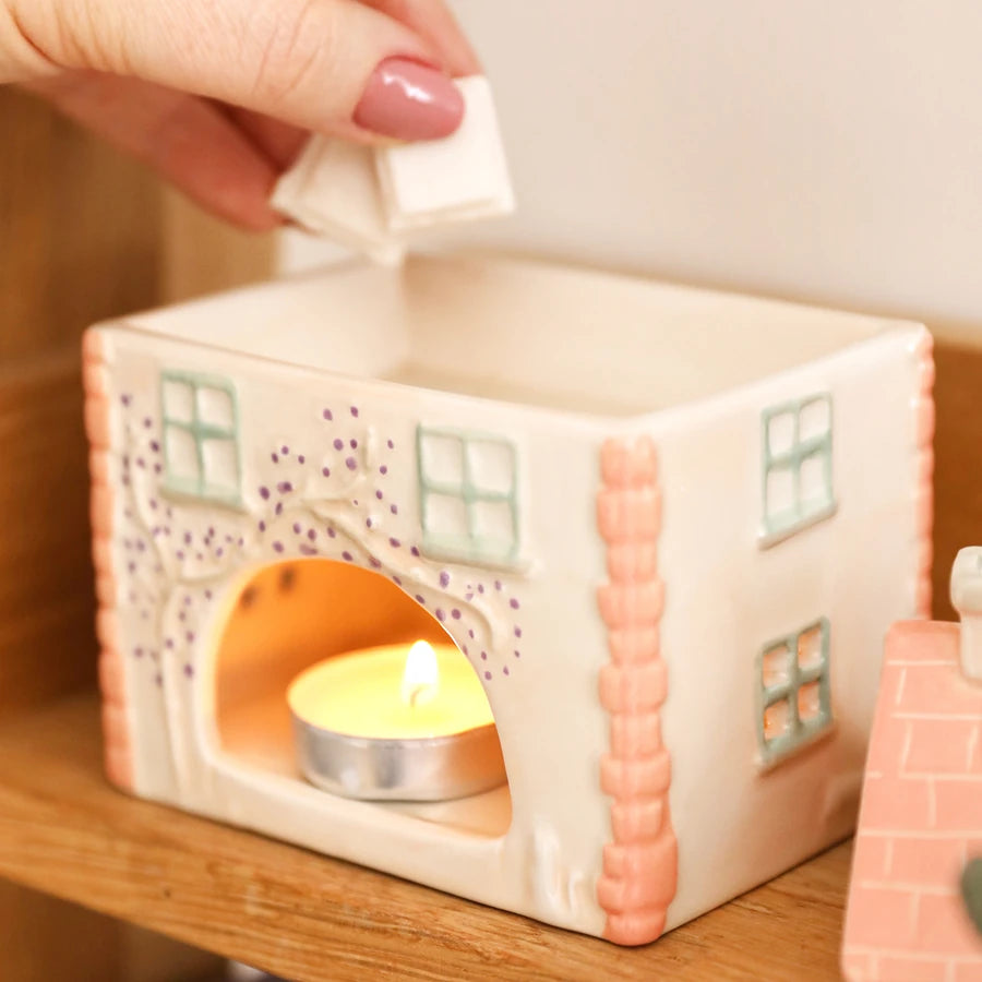 A ceramic house-shaped candle holder with a lit tea light candle inside 83062 Uneeka