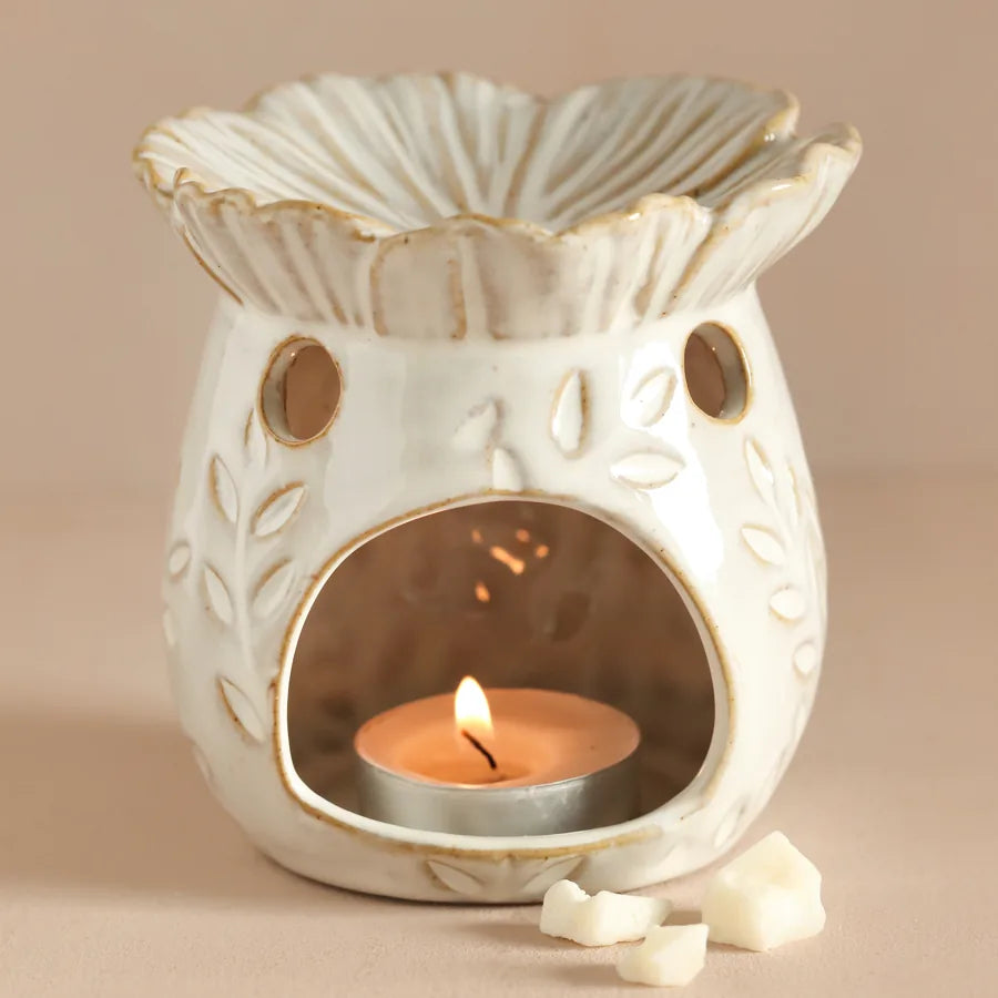 'Secret Garden' Decorative ceramic oil burner with a lit candle inside on a beige background 63092 Uneeka
