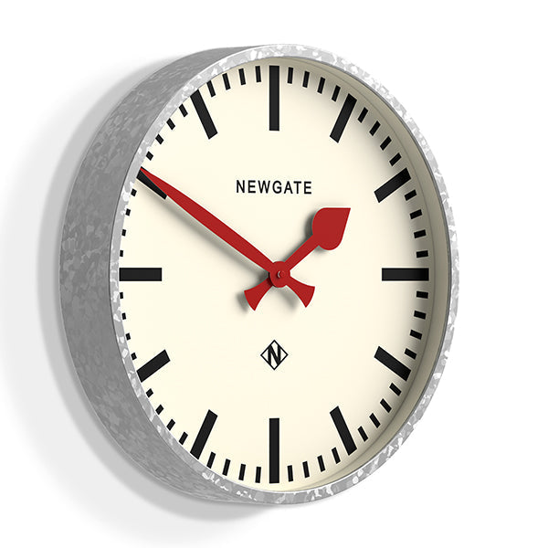 A large galvanised station wall clock with a bold marker dial, contrasting red hands and deep straight-cut metal case with a galvanised finish